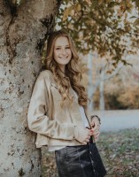 Abigail smiles in front of a tree